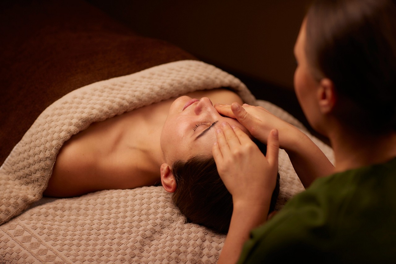 Spa therapist giving a woman a facial treatment.
